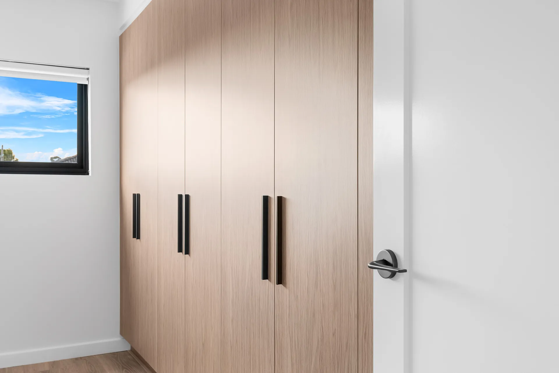 Bedroom built-in wardrobe with timber doors and black handles in the Scott home