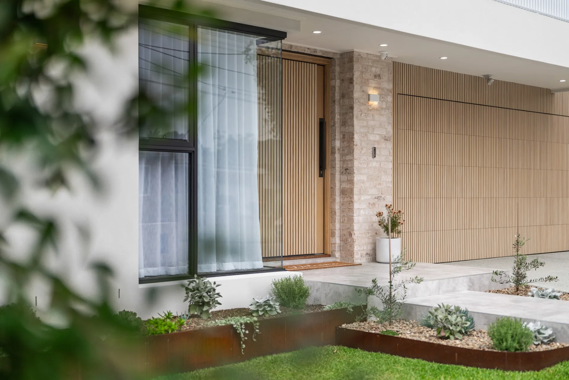 Front entry with timber batten door, recycled brick and vertical cladding at the Scott home