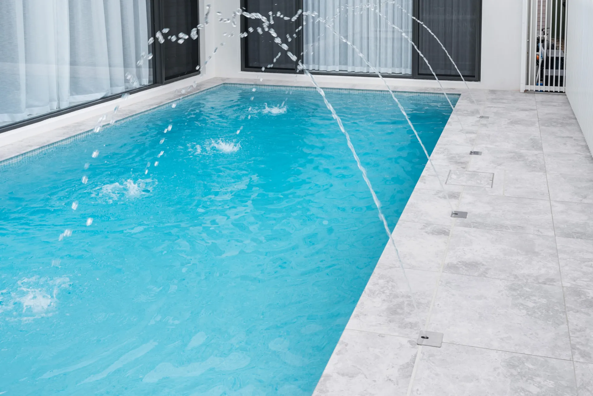 Pool with water features and frameless glass fencing at the Scott home