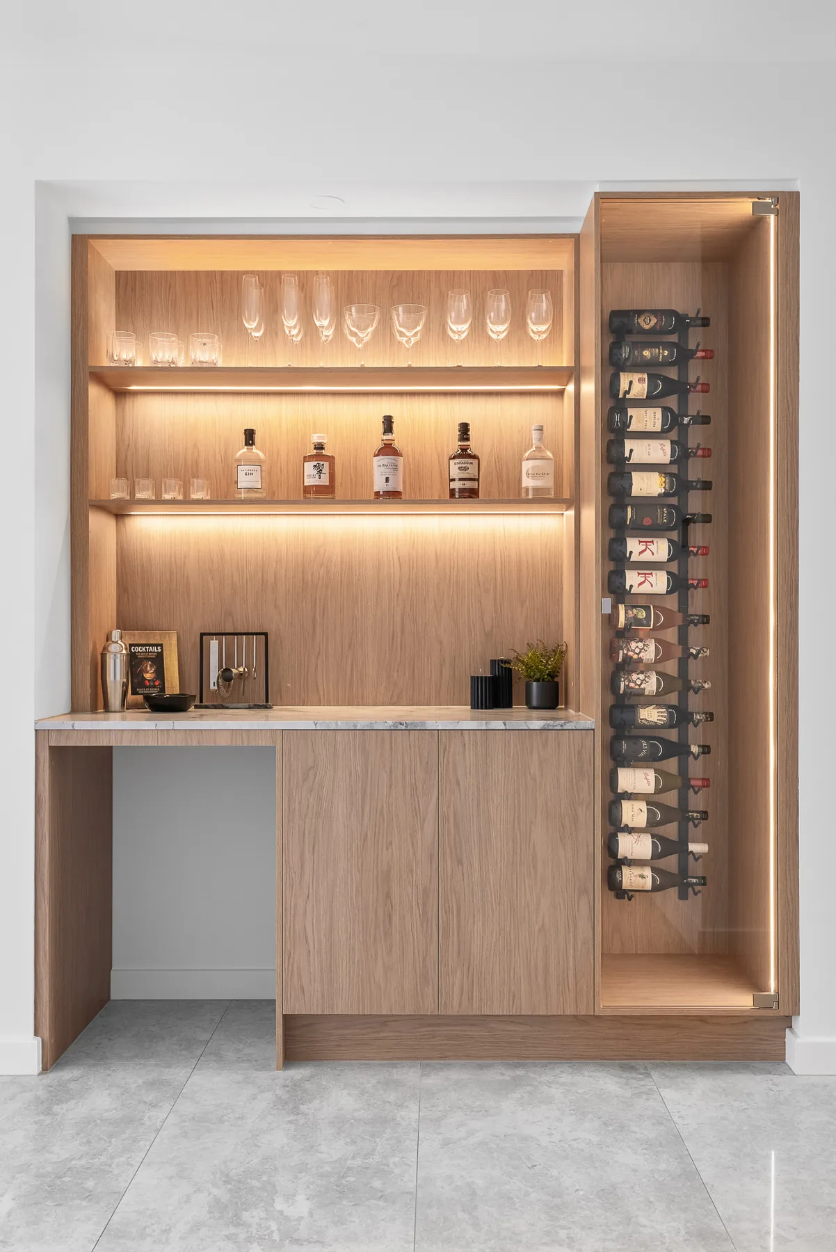 Built-in drinks bar with backlit oak shelving and glass wine display in the Scott home
