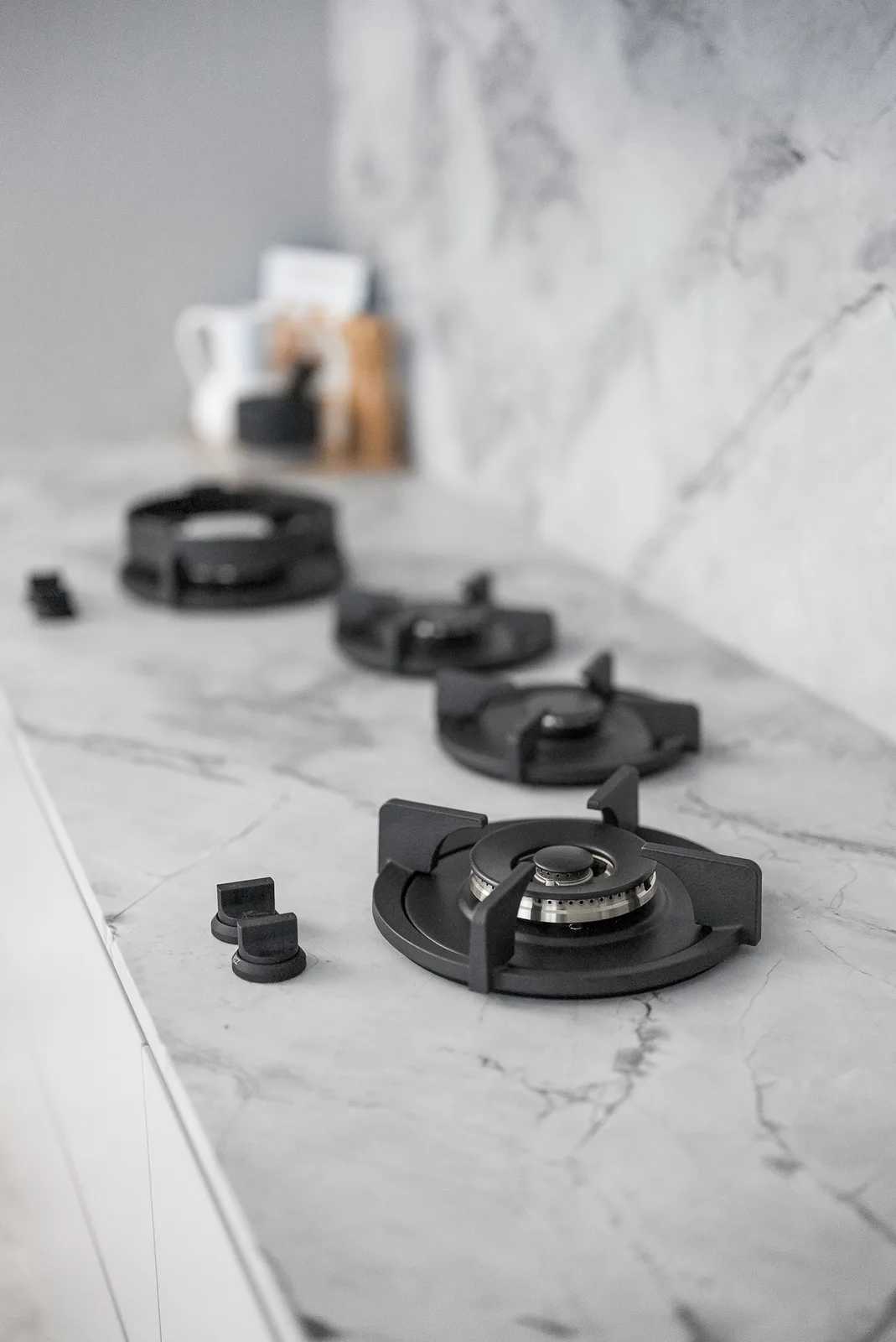 Black gas cooktop burners on the marble kitchen benchtop in the Scott home