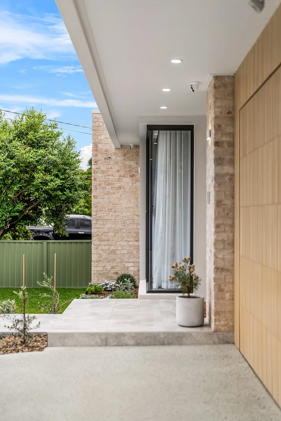 Entry portico with recycled brick, timber batten cladding and landscaped garden at the Scott home